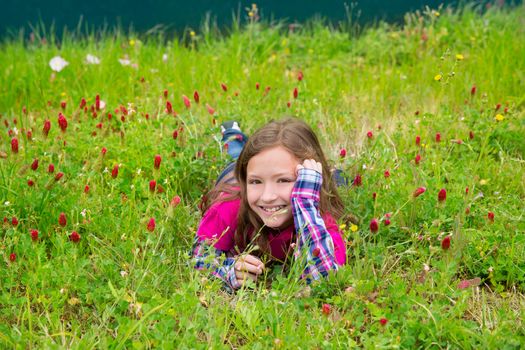 Happy relaxed kid girl smiling on a spring flowers meadow with green grass