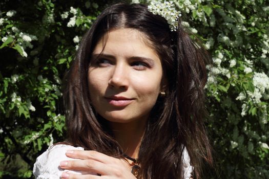 Beautiful young woman on bird-cherry tree background