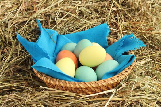 Basket of colored easter eggs in basket on hay