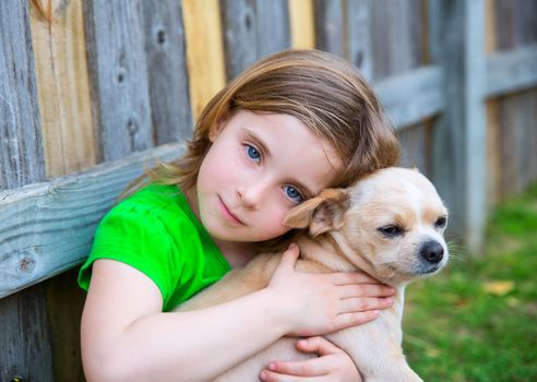 Blond happy girl with her chihuahua doggy portrait on backyard fence