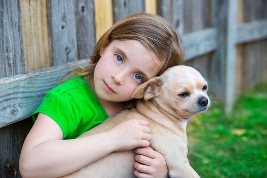 Blond happy girl with her chihuahua doggy portrait on backyard fence