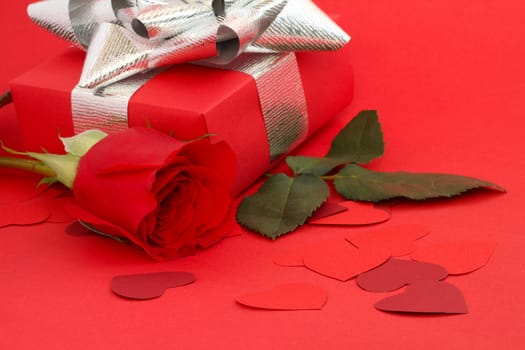 Valentines Day gift in box with rose and small hearts on red background