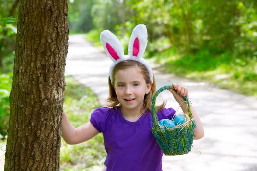 Easter girl with eggs basket and funny bunny ears on the forest