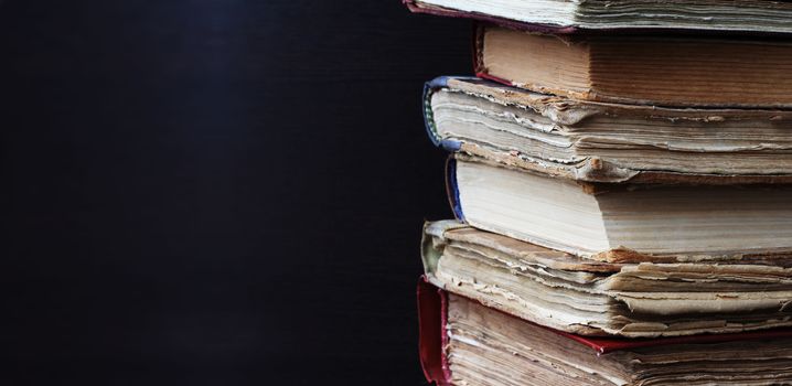 Corner of old books stack on dark background