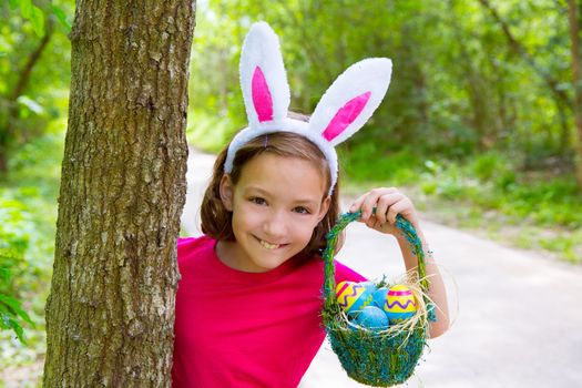 Easter girl with eggs basket and funny bunny face expression at the forest