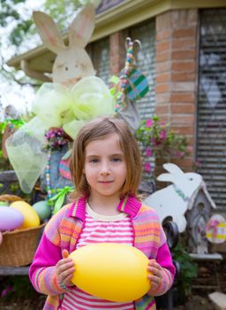 Easter blond girl holding big yellow egg and bunny in background