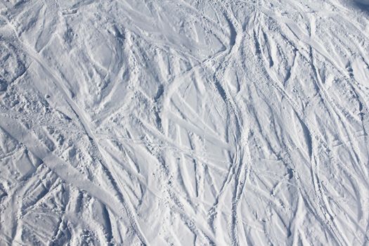 Ski traces on snow in mountains at sunny day