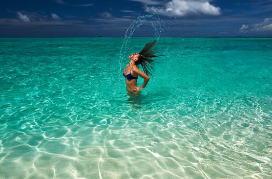 Woman splashing water with her hair in the ocean