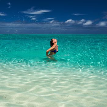 Woman splashing water with her hair in the ocean