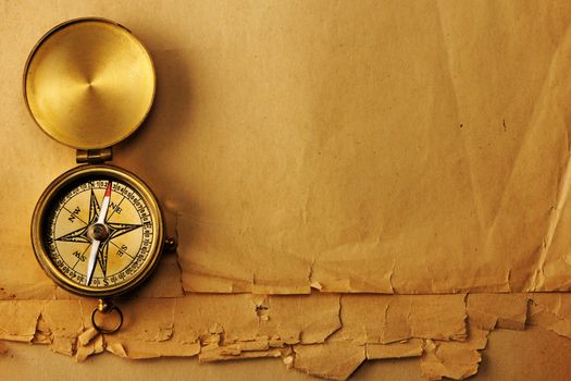 Antique brass compass over old paper background