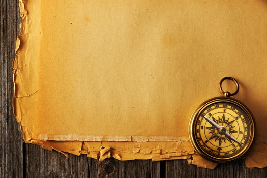 Antique brass compass over old paper background