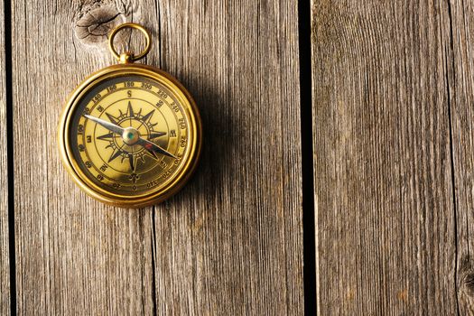 Antique brass compass over wooden background