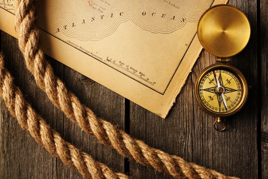 Antique brass compass and rope over old map