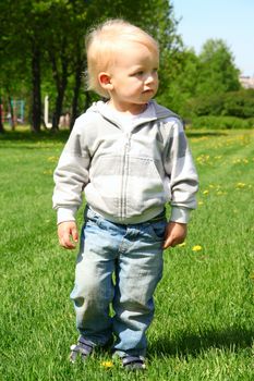 Small boy walking on spring grass field
