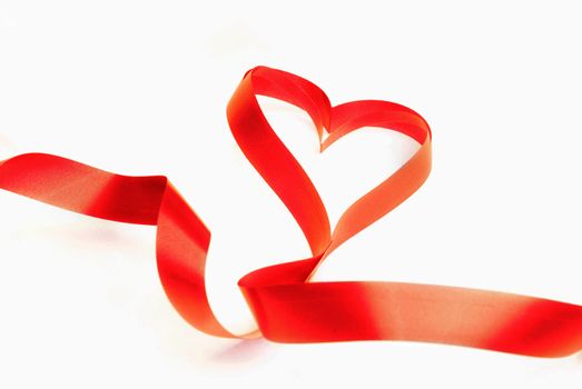 Red ribbon in the shape of heart as a symbol of love