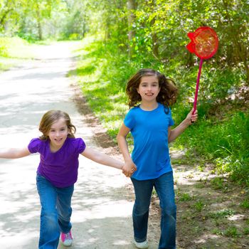 Friends and sister girls running in the forest track smiling happy with butterfly net