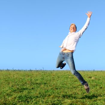 Happy young man jumping on summer green field
