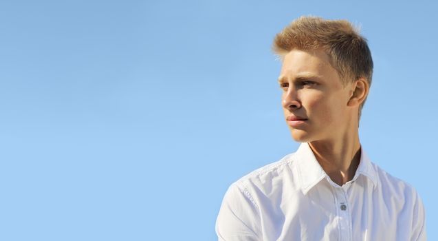 Handsome blond man on blue sky background at sunny day