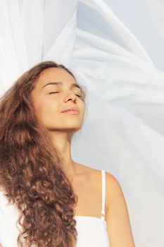 Beautiful young woman with closed eyes on white fabric background