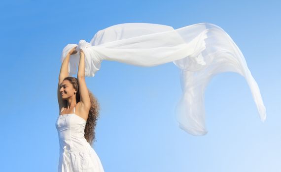 Portrait of a young woman wearing dress holding white fabric outdoors