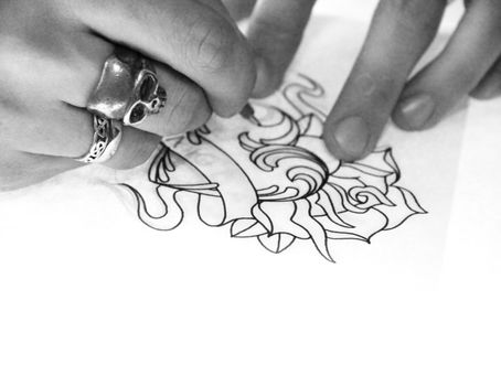 Artist drawing sketch of tattoo on white paper bw