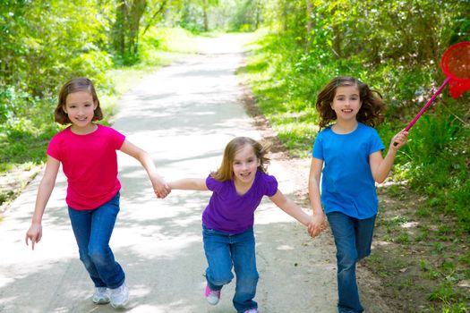 Friends and sister girls running in the forest track smiling happy with butterfly net