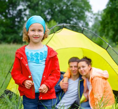 Young girl with his family near tent in camping on the nature