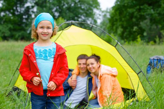 Young girl with his family near tent in camping on the nature