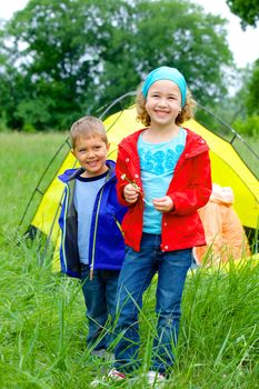 Summer, family camping - lovely sister and brother with parents near camp tent. Vertical view