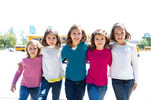 school girls friends sisters in a row walking from yellow school bus lot