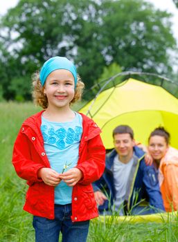 Young girl with his family near tent in camping on the nature