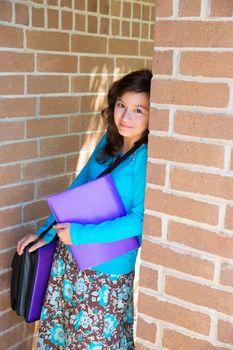 Schoolgirl teenager at school brick wall happy with folder and bag