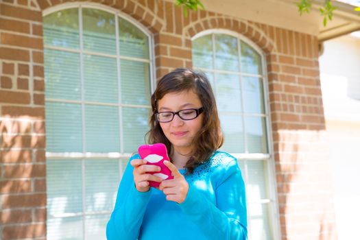 Teenager girl with glasses playing with pink smartphone smiling