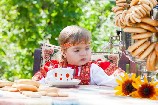 Girl in Russian national dress drinks tea from a samovar