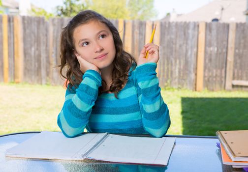 American latin teen girl thinking with pencil doing homework on backyard