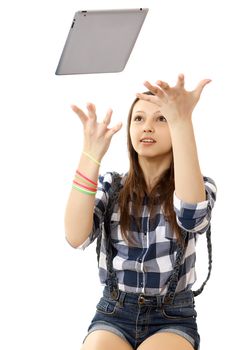 Girl catches flying in air Tablet PC. Caucasian teenage girl,wearing a plaid shirt and short denim shorts, throws up in the air PC tablet. One person, teenager, female, Caucasian, vertical, isolated. 