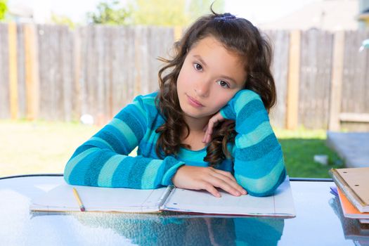 American latin teen girl relaxed on table doing homework on backyard