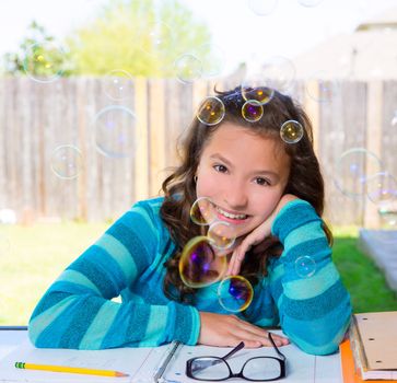American latin teen girl with soap bubbles doing homework on backyard