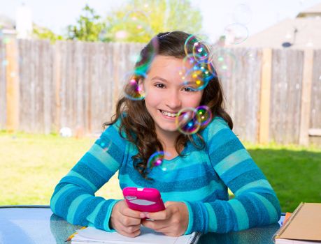 American latin teen girl with smartphone doing homework on backyard