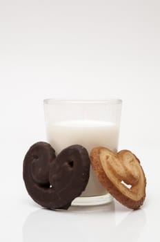 glass of milk with heart shaped cookies on a white background