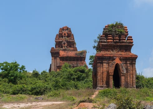 Vietnam: Three Banh It Cham towers on the green hill against blue skies.