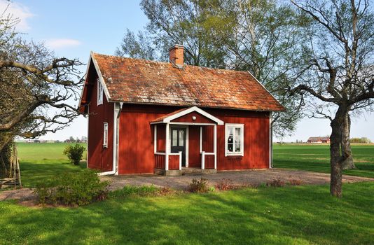 Old red cottage surrounded by farmland.