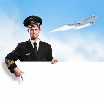 pilot in the form of holding an empty billboard on the background of sky and flying plane, place for text