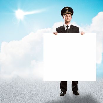 pilot in the form of holding an empty billboard on the background of sky with clouds, place for text