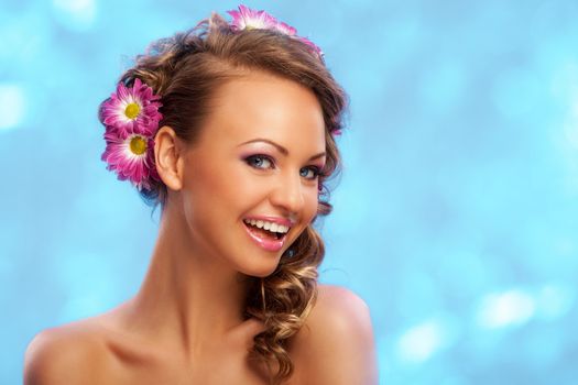 Beautiful young caucasian woman with flowers in her hair over blue background