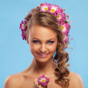 Beautiful young caucasian woman with flowers in her hair over blue background