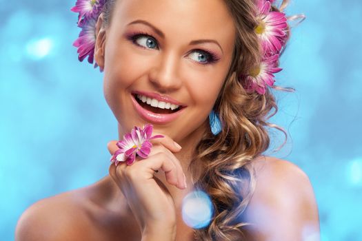 Beautiful young caucasian woman with flowers in her hair over blue background