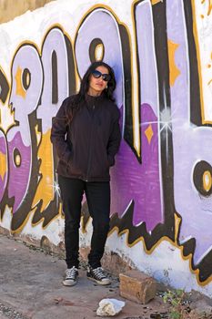 Woman in black at the graffiti brick wall