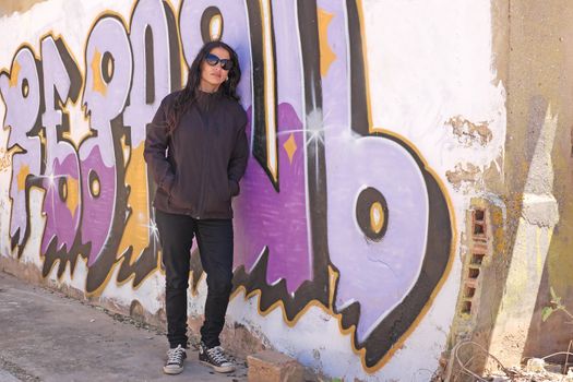 Woman in black at the graffiti brick wall
