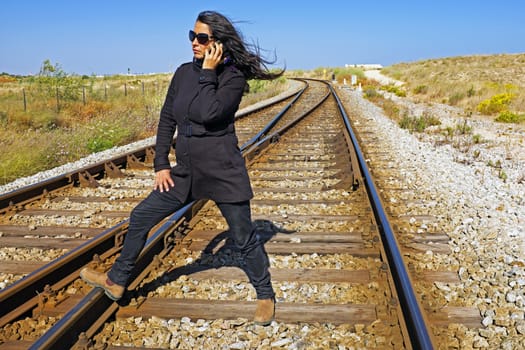 Woman making a phone call at a railroad track